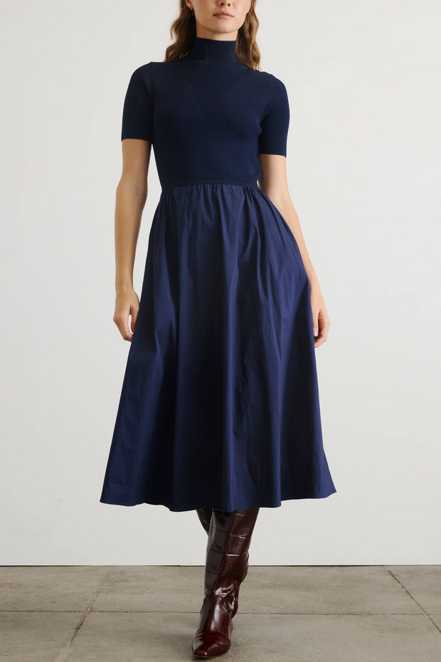 Woman wearing a navy blue dress with a plain background