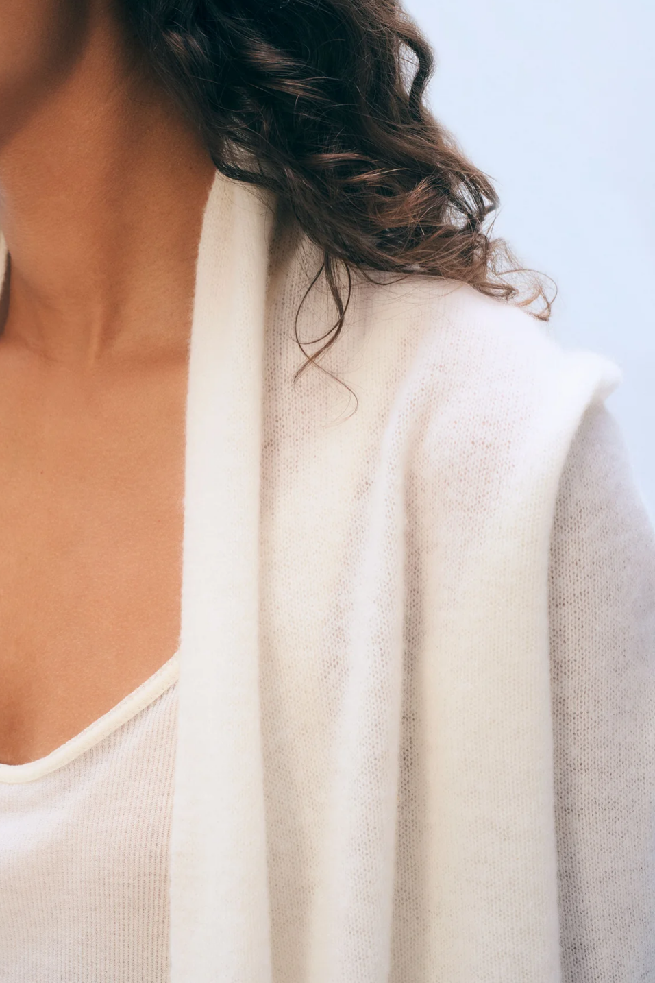 Close-up of a person wearing a white cardigan against a light background