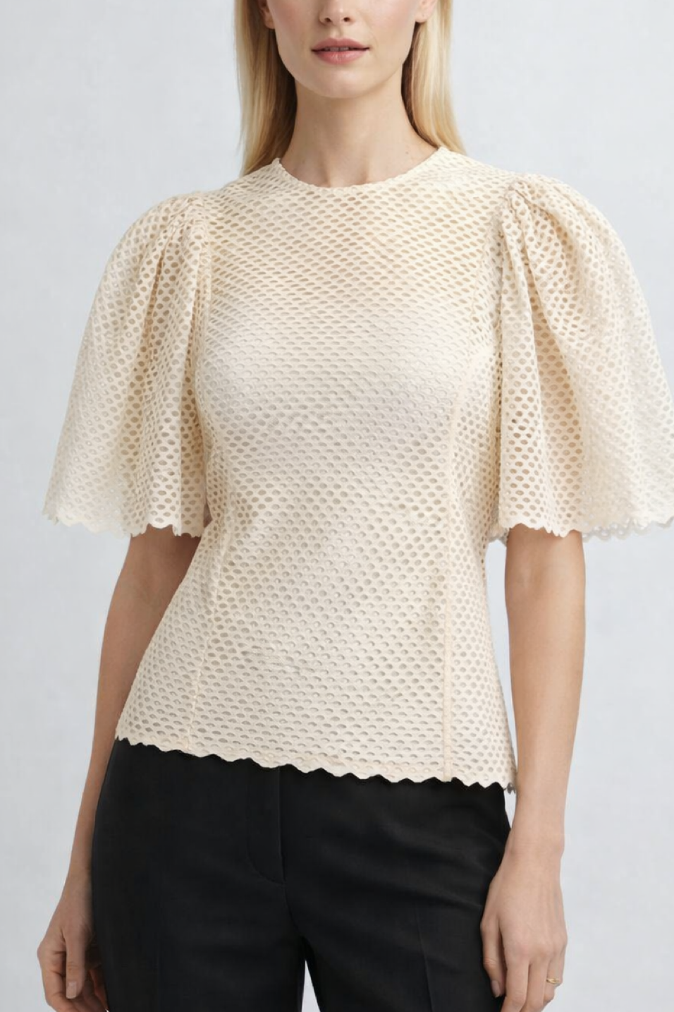 Woman wearing a beige textured blouse with puffed sleeves on a plain background