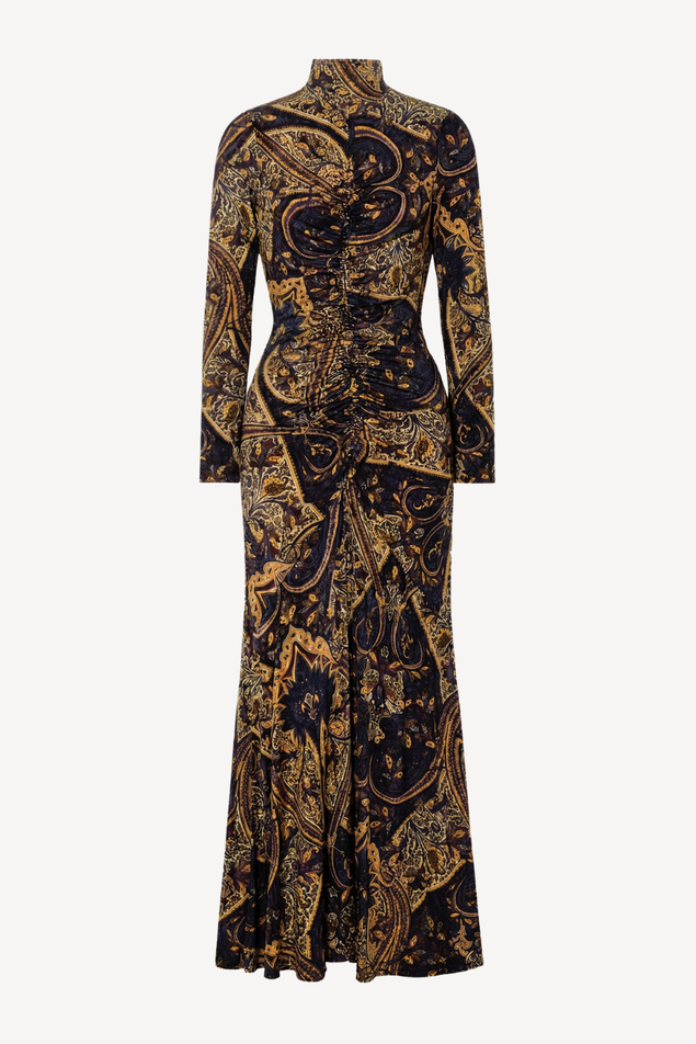 A long-sleeved high-neck maxi dress with a fitted waist and flared skirt, featuring an intricate gold and brown paisley pattern on a black base, shown against a light gray background.