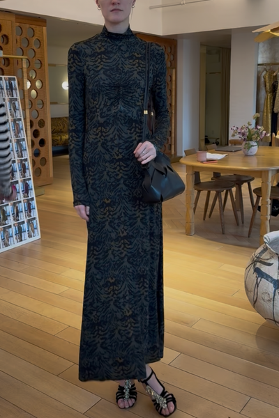 Person wearing a long black lace dress in an indoor setting
