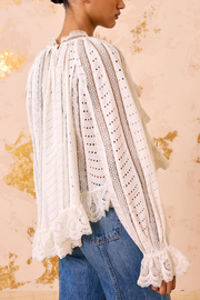 White lace blouse with blue jeans against a decorative background