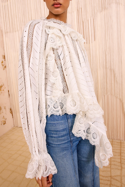 White lace top worn by a person with a neutral background