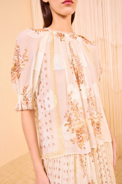 Woman wearing a floral embroidered outfit against a beige background