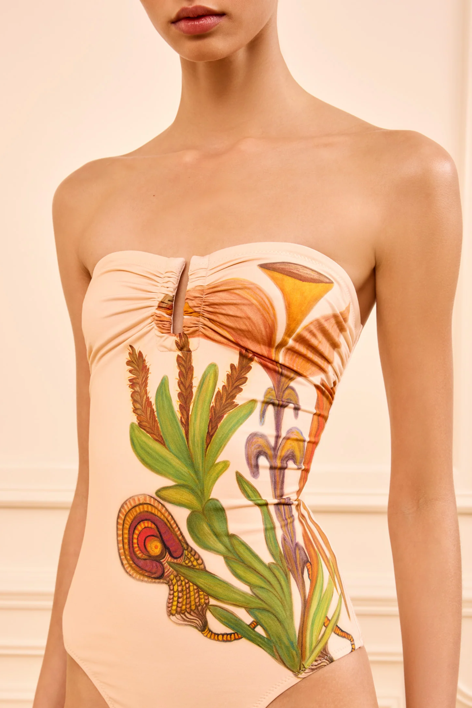 Beige strapless bathing suit with tropical leaf design on a neutral background