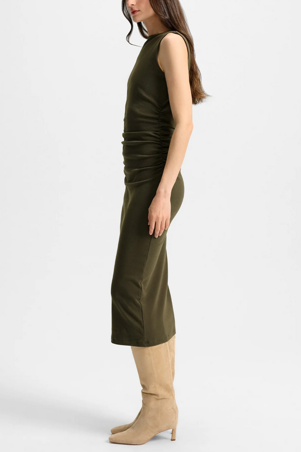 Woman wearing a green dress with beige boots on a white background