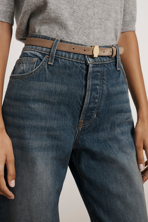 Person wearing blue jeans with a Bark suede belt on a plain background