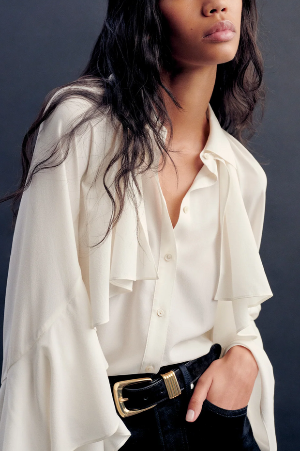 Woman wearing a blouse with a black belt against a dark background