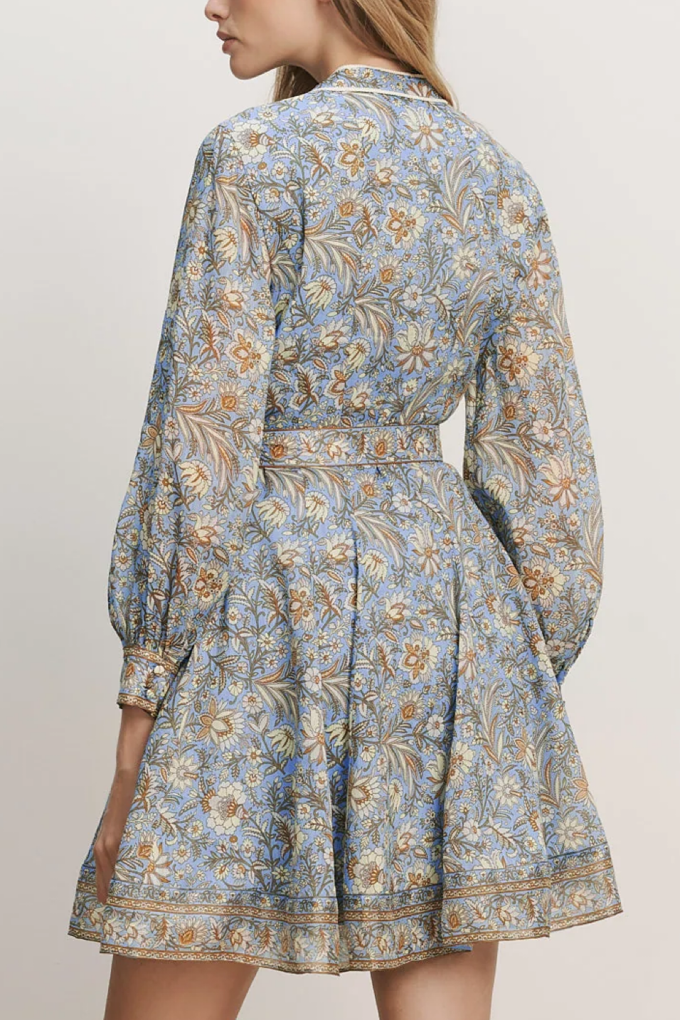 Woman wearing a blue floral dress against a plain background