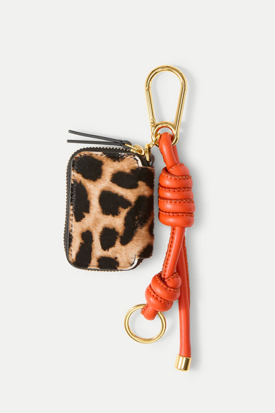 Leopard print coin purse with orange keychain on a white background