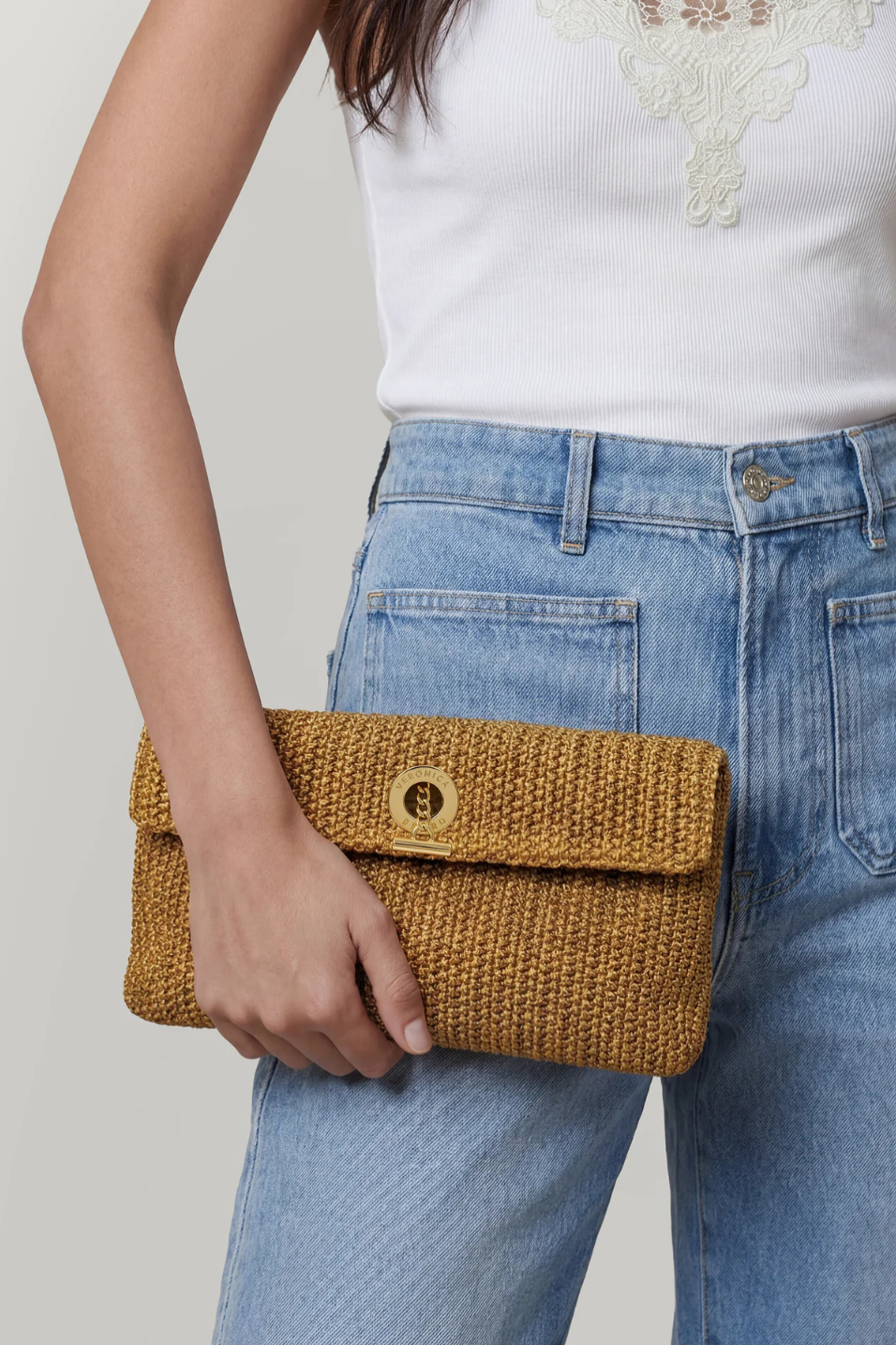 Person holding a woven clutch bag with a plain background