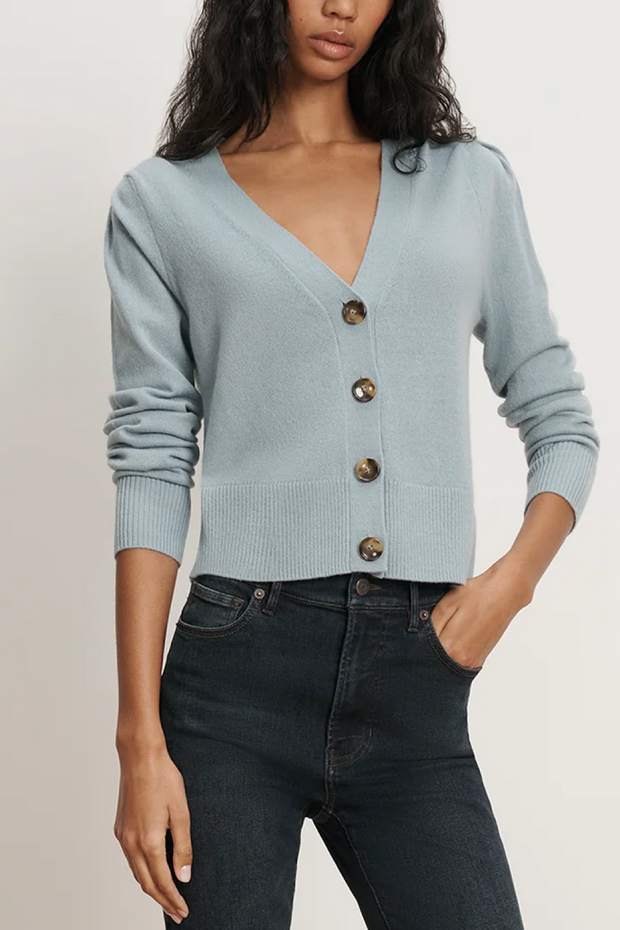 Woman wearing a light blue cardigan with buttons on a plain background