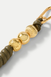 Gold and olive green beaded keychain on a light gray background