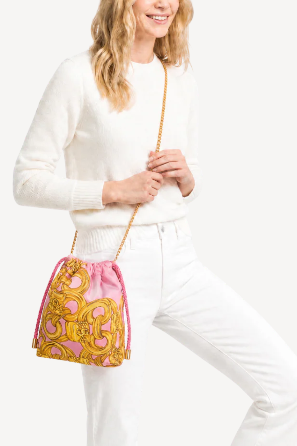 Woman holding a pink and gold patterned handbag against a white background