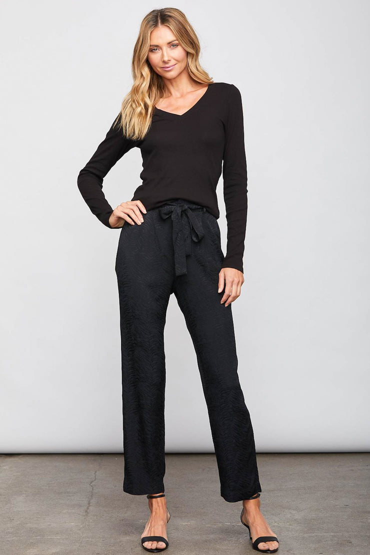Image of model wearing the SUNDAYS Malone Pant, standing infront of grey backdrop, front view with hand on hip